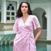 Discover Candy Floss by The Sootee — a pink Shibori cotton wrap dress with a V-neckline, flutter sleeves, and side pockets. Hand-dyed and fully lined, this artisanal slow-fashion piece blends playful charm with effortless feminine sophistication.