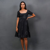 Discover Nyra by The Sootee — a graceful black Bandhani mulmul cotton dress with a wide square neckline, short sleeves, and A-line flare. Handcrafted for slow-fashion lovers, it features artisanal tie-dye motifs, side pockets, and a back tie-up for effortless day-to-evening elegance.