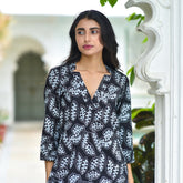 Woman wearing a black and white patterned dress standing outdoors.