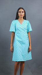 Discover Ambr by The Sootee — a breezy sky blue Bandhani cotton wrap dress with a flattering V-neckline, short sleeves, and side pockets. Hand-tied and dyed using traditional techniques, this sustainable slow-fashion piece blends artisanal craft with everyday comfort and uniqueness.